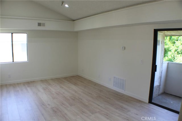 unfurnished room with vaulted ceiling, baseboards, visible vents, and light wood-style floors