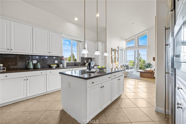 13031 Villosa Pl Unit 437, Playa Vista, CA 90094 - kitchen with a center island, high vaulted ceiling, white cabinets, backsplash, and light tile patterned flooring