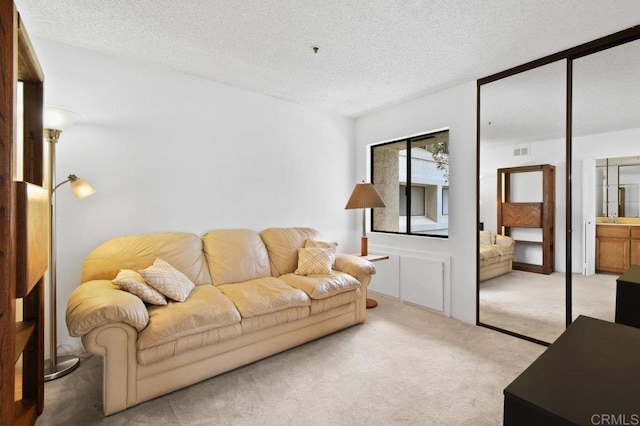 living room with a textured ceiling, visible vents, and light colored carpet