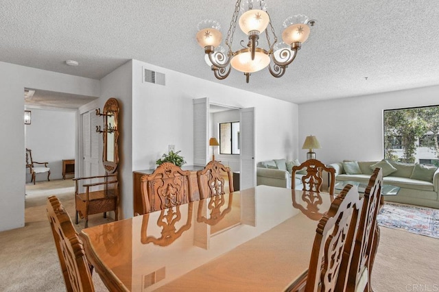 dining space with a textured ceiling, a chandelier, visible vents, and light colored carpet