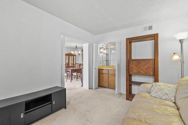 living area with light colored carpet, an inviting chandelier, a textured ceiling, and visible vents