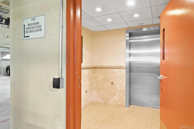 interior space with a drop ceiling, elevator, and recessed lighting