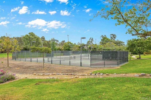 view of sport court featuring fence and a lawn