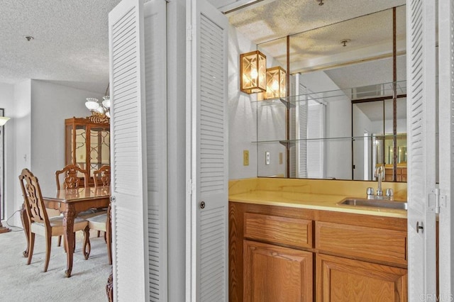 bathroom featuring a notable chandelier, vanity, and a textured ceiling