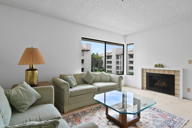 carpeted living area with a tile fireplace and a textured ceiling