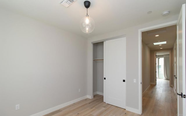 unfurnished bedroom featuring a closet, visible vents, light wood-style flooring, and baseboards