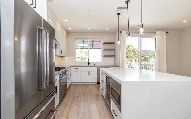 kitchen with recessed lighting, light wood finished floors, a sink, high end appliances, and open shelves