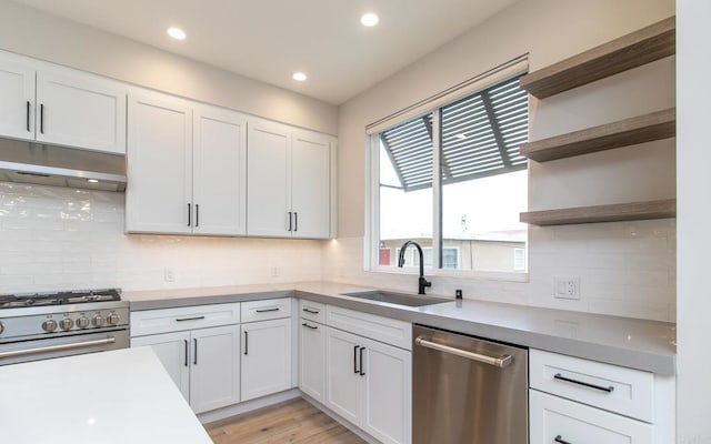 kitchen featuring a sink, open shelves, under cabinet range hood, white cabinets, and appliances with stainless steel finishes