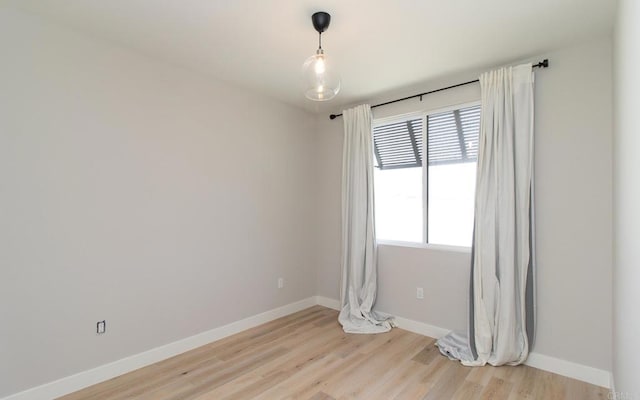 spare room with baseboards and light wood-style flooring