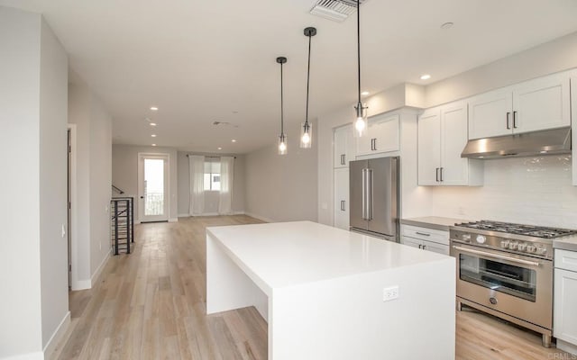 3341 Tyler St, Carlsbad, CA 92008 - kitchen with premium appliances, under cabinet range hood, tasteful backsplash, a kitchen island, and light wood-type flooring