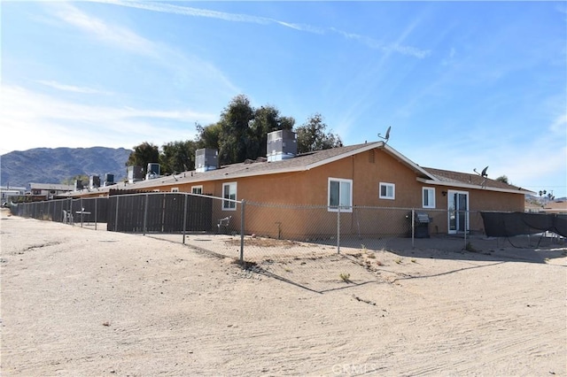 view of side of home with central air condition unit, a mountain view, and fence