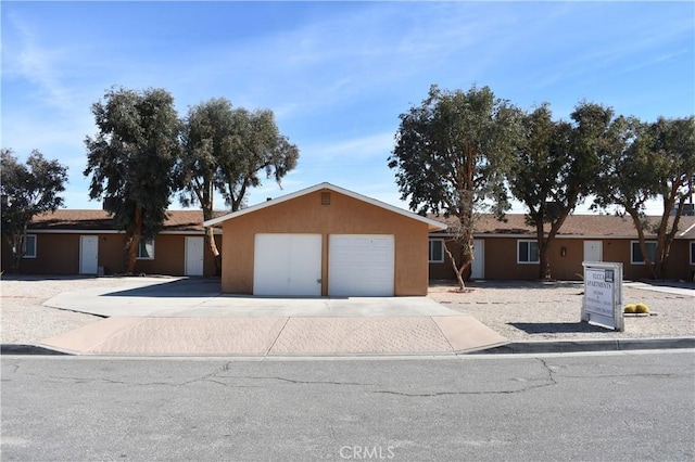 single story home featuring a garage, stucco siding, and driveway