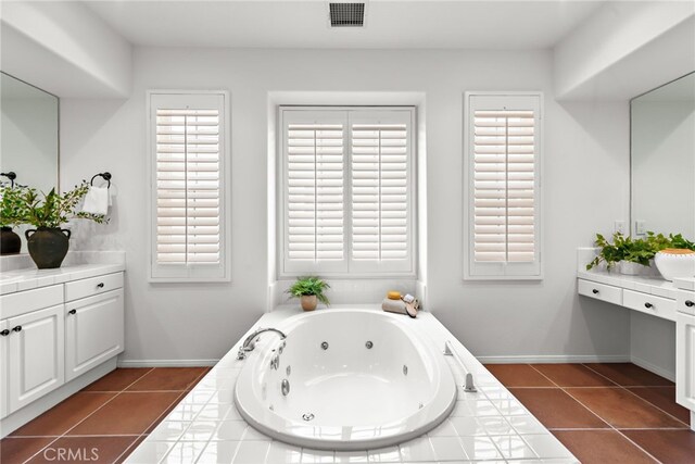 bathroom featuring tile patterned flooring, a tub with jets, baseboards, and vanity