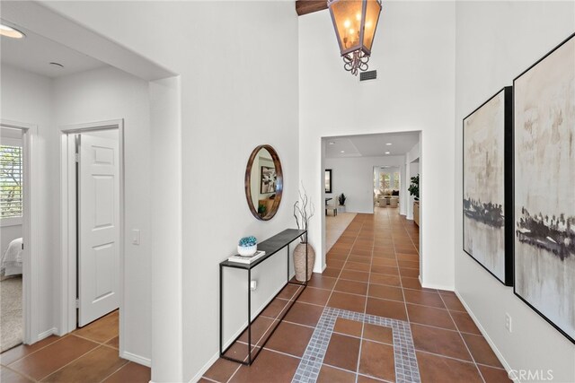 corridor with dark tile patterned floors, a high ceiling, and baseboards