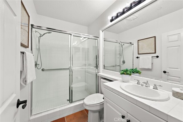 bathroom with a shower stall, toilet, tile patterned flooring, vanity, and a textured ceiling