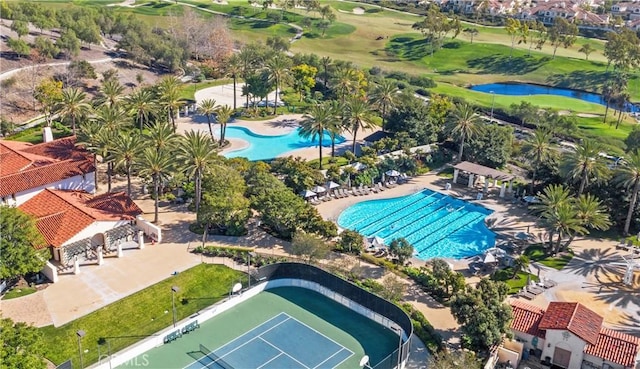 bird's eye view of a pool, a nearby body of water, and a golf course
