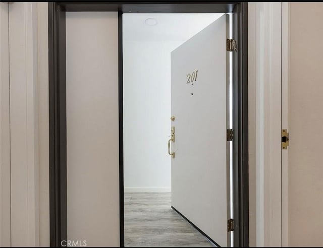 corridor with wood finished floors and baseboards