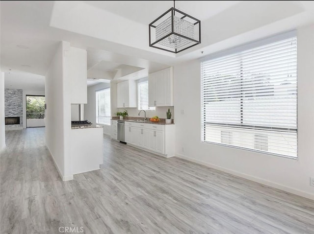 kitchen with dishwasher, open floor plan, white cabinetry, light wood finished floors, and baseboards