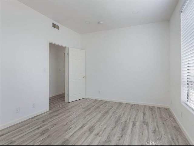 unfurnished room with light wood-type flooring and baseboards