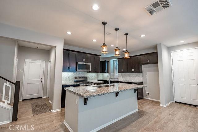 24189 Darmera Dr, Lake Elsinore, CA 92532 - kitchen with stainless steel appliances, light wood finished floors, light stone counters, backsplash, and recessed lighting
