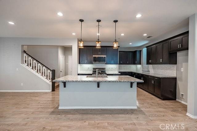 24189 Darmera Dr, Lake Elsinore, CA 92532 - kitchen featuring appliances with stainless steel finishes, light wood-style floors, light stone counters, a sink, and recessed lighting