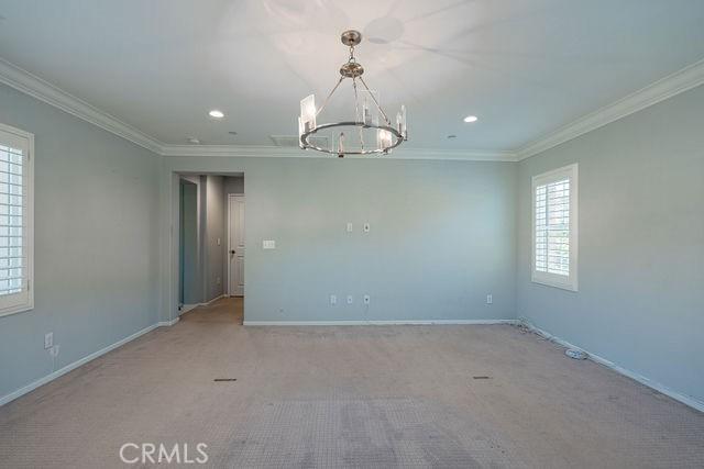 24189 Darmera Dr, Lake Elsinore, CA 92532 - empty room with a chandelier, crown molding, baseboards, recessed lighting, and carpet floors
