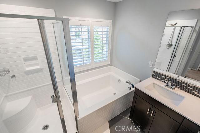 24189 Darmera Dr, Lake Elsinore, CA 92532 - bathroom featuring a shower stall, a bath, vanity, and backsplash