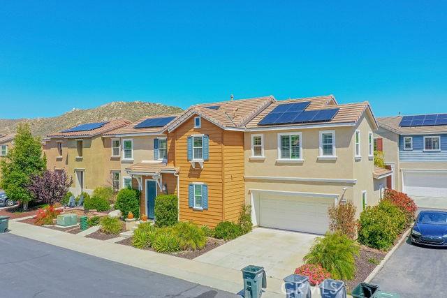 24189 Darmera Dr, Lake Elsinore, CA 92532 - view of front of home featuring a garage, concrete driveway, solar panels, stucco siding, and a mountain view