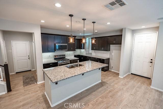 24189 Darmera Dr, Lake Elsinore, CA 92532 - kitchen featuring appliances with stainless steel finishes, a sink, light wood-style floors, a center island with sink, and recessed lighting