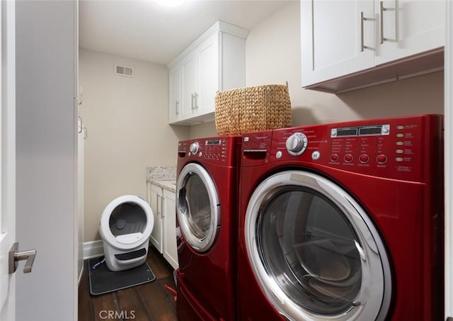 laundry room with cabinet space, visible vents, dark wood-style flooring, washing machine and dryer, and baseboards