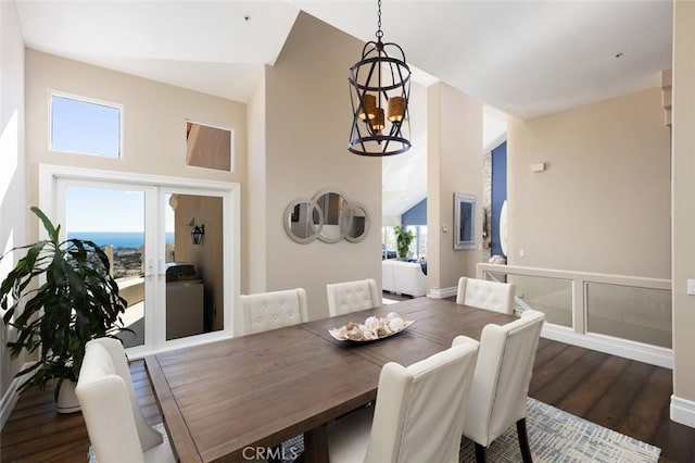 dining space with vaulted ceiling, a notable chandelier, baseboards, and dark wood finished floors