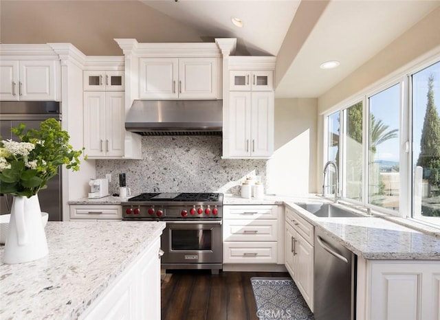kitchen with a sink, stainless steel appliances, white cabinetry, under cabinet range hood, and lofted ceiling