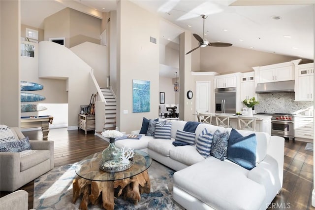 living room with a ceiling fan, stairway, high vaulted ceiling, and dark wood-style floors