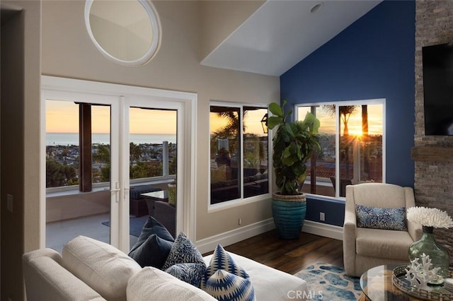 sunroom with a water view, baseboards, wood finished floors, and lofted ceiling