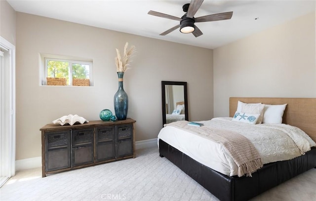 bedroom featuring light carpet, baseboards, and a ceiling fan