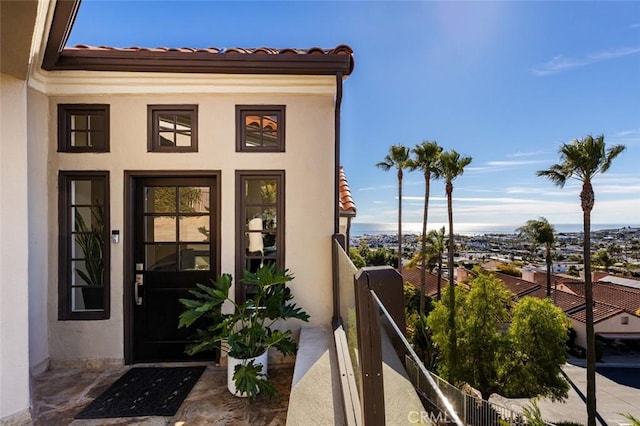 property entrance with a tile roof, stucco siding, and a balcony