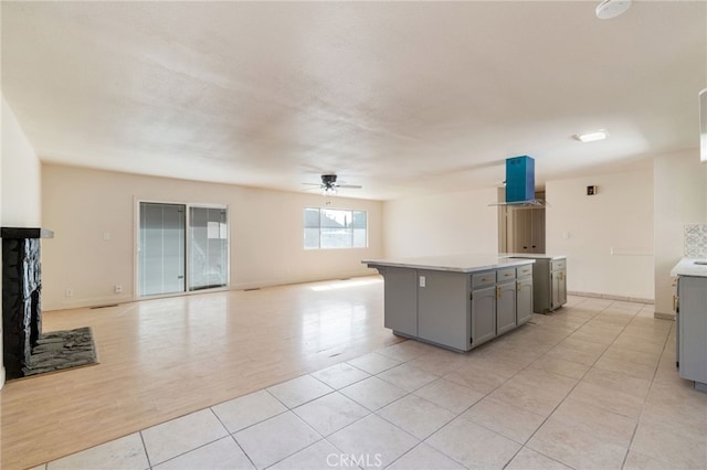 2738 S Fairway Ct, Visalia, CA 93277 - kitchen with light countertops, a ceiling fan, wall chimney range hood, open floor plan, and gray cabinetry