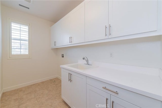 washroom with baseboards, visible vents, washer hookup, a sink, and cabinet space