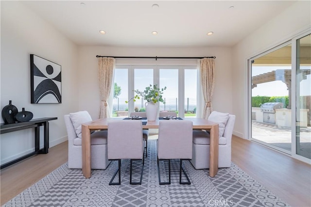 dining space with baseboards, light wood-type flooring, and recessed lighting