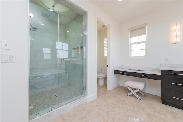bathroom with toilet, a stall shower, tile patterned floors, baseboards, and vanity