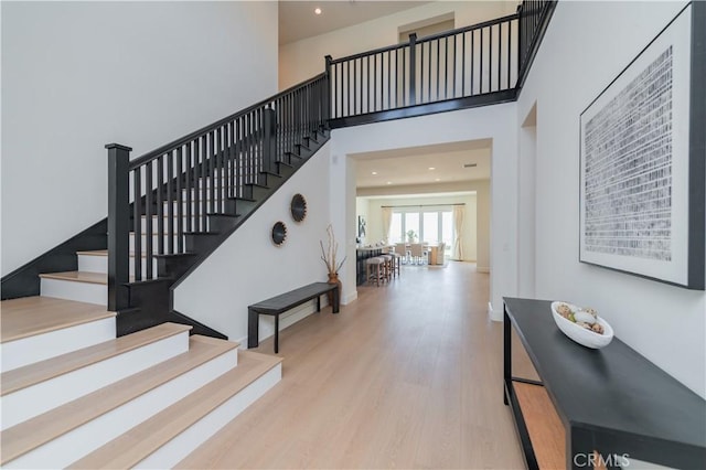 stairs featuring recessed lighting, a towering ceiling, and wood finished floors