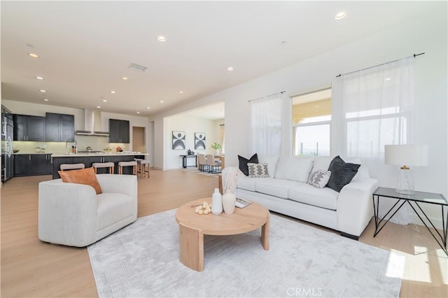 living area featuring light wood finished floors, recessed lighting, and visible vents