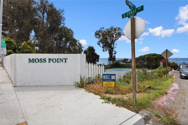 community sign with a water view and fence