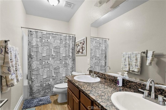 full bath featuring a sink, toilet, visible vents, and wood finished floors