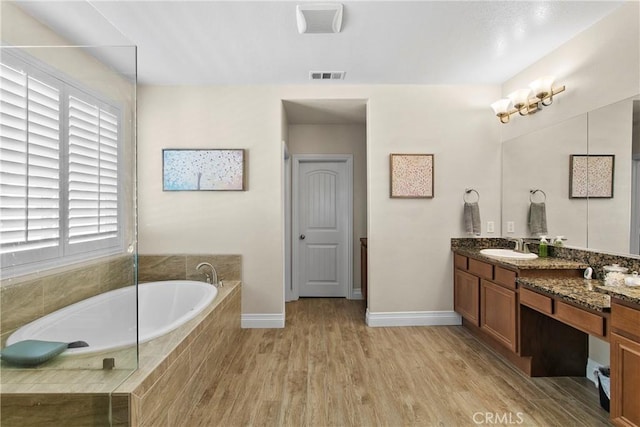 full bathroom featuring wood finished floors, a bath, visible vents, baseboards, and vanity