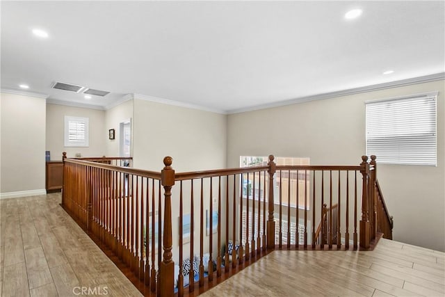 hallway featuring light wood-style floors, an upstairs landing, ornamental molding, and recessed lighting