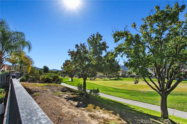 surrounding community featuring a yard, fence, and view of golf course