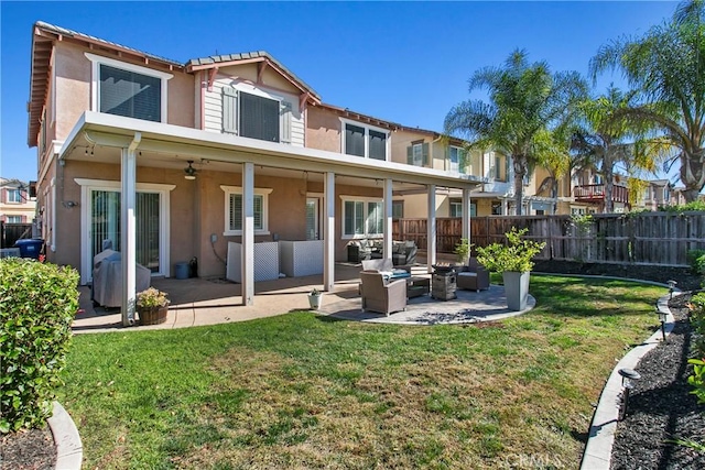 rear view of house with a yard, outdoor lounge area, ceiling fan, stucco siding, and a fenced backyard