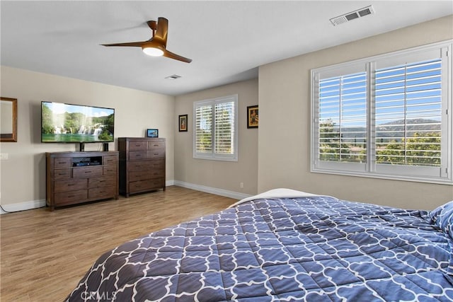 bedroom featuring baseboards, visible vents, a ceiling fan, and wood finished floors