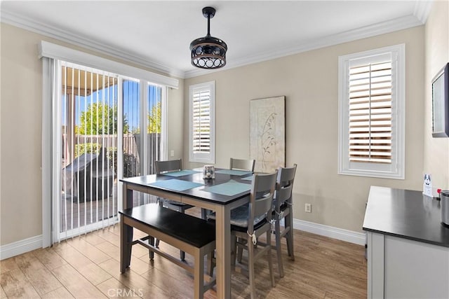 dining space with ornamental molding, baseboards, and light wood-style floors